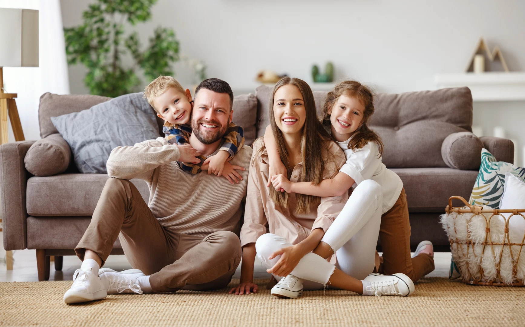 Family Dermatology Care A happy family of four smiling together in a living room.